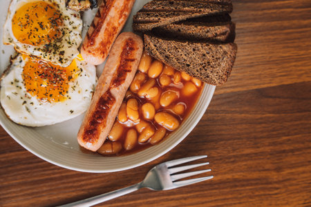 Fried eggs with sausages and rye bread on a white plate with a fork