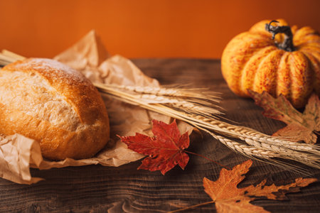 Fresh loaf of bread with ears of wheat and pumpkin on a wooden backgroundの写真素材
