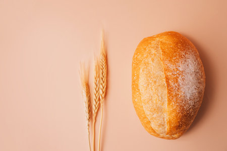 Fresh loaf of bread with ears of wheat on the tableの写真素材