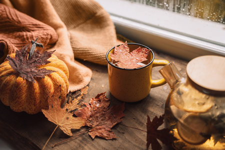 Herbal tea with lemon in a glass teapot next to a mug on a wooden table with maple leavesの写真素材