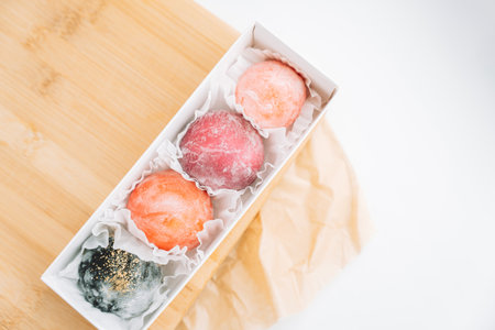Delicious colored mochi in a box on a wooden boardの写真素材