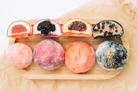 Whole and cut colored mochi on a wooden boardの写真素材