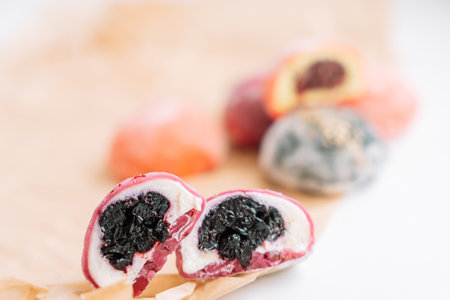 Half colored mochi with berry filling on a wooden board on a white backgroundの写真素材