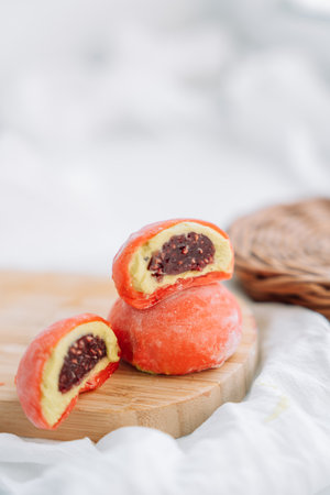 Orange half mochi with berry filling on a wooden boardの写真素材