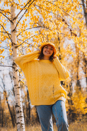 Lady in a yellow knitted sweater and hat walks through the autumn forestの写真素材