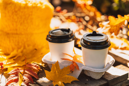 Two cups of coffee on a wooden pallet outdoors against yellow leavesの写真素材