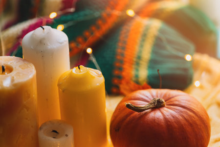 Cozy atmosphere with candles, pumpkin and knitted cardigan with garlandの写真素材