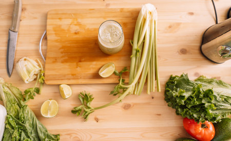Prepared celery smoothie on a wooden table with fresh vegetables on itの写真素材