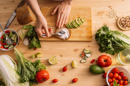 Lady spreading sauce on bread for vegetarian sandwich on wooden tableの写真素材
