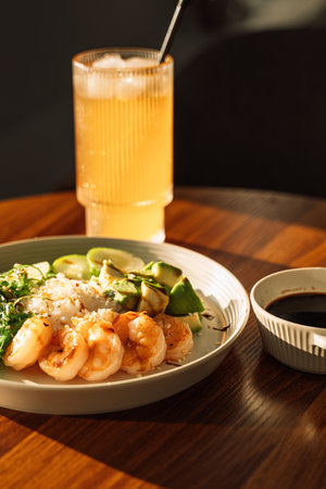 Light snack of avocado and shrimp with cool drink in round plate on wooden tableの写真素材