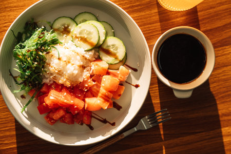 Light snack of red fish and vegetables with soy sauce in a round plate on a wooden tableの写真素材