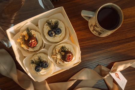 Delicious cupcakes in a box decorated with chocolate in the shape of Christmas tree decorations with a cup of coffeeの写真素材