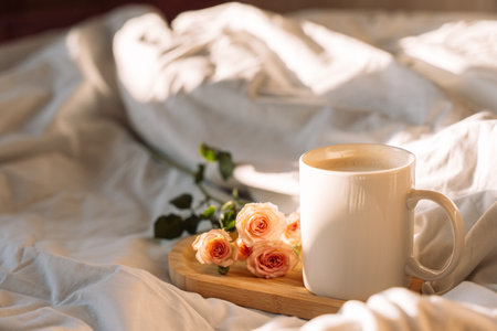 Glass of coffee with flowers on a wooden tray on a white bedの写真素材