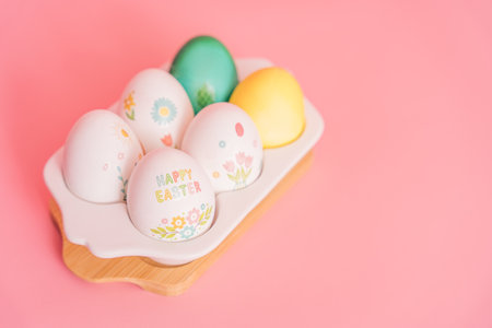 Easter eggs of different colors and in stickers in a white tray on a pink background
