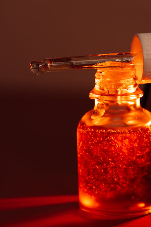 A drop of serum flows from a pipette onto a red jar