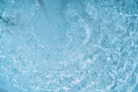 Stream of water flows from a faucet into a swimming poolの写真素材