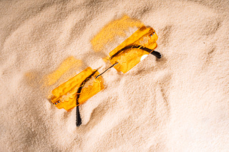 Yellow razor shaped sunglasses on clean sandの写真素材