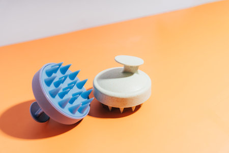 Blue and white massager for scalp on an orange background