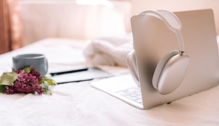 Cozy workplace with wireless headphones on laptopの写真素材