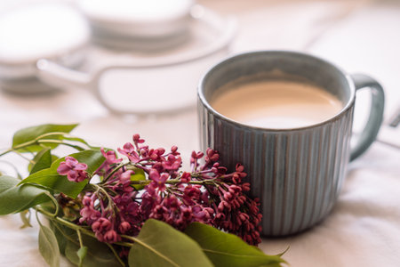 Cup of coffee with a sprig of lilac in front of wireless headphones on a white backgroundの写真素材