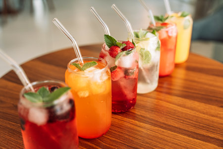 Fruit drinks with berries and ice in glass glasses and straws on a wooden table