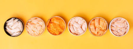 Multi-colored snus sachets with different flavors are placed in jars on a yellow backgroundの写真素材