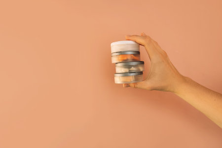 Hand holding plastic jars filled with snus against brown backgroundの写真素材