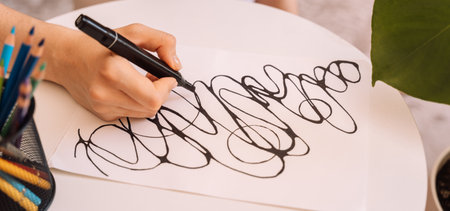 Lady draws with a black felt-tip pen on a white sheet