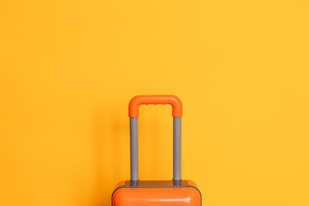 Orange suitcase against a yellow backgroundの写真素材