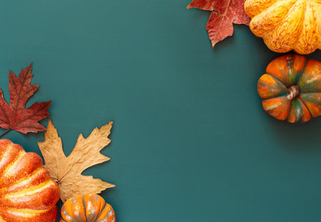 Pumpkins and dry maple leaves in the corners of green backgroundの写真素材