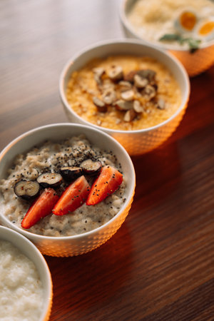 4 types of porridge in white bowls on a wooden background, oatmeal, corn, millet and rice.の写真素材