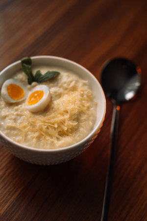 millet porridge with egg in a white bowl on a dark background.の写真素材