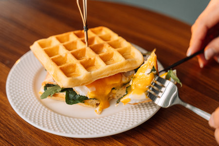 Breakfast homemade Belgian waffle sandwich with egg, fork in hand.の写真素材