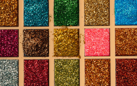 Close-up of colorful glitter eyeshadows in used palette. Textured beauty concept with bold sparkle.の写真素材