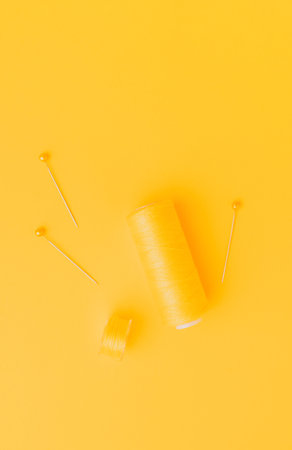 Yellow sewing thread and pins on bright backgroundの写真素材