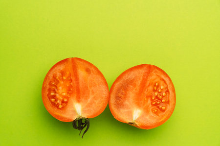 Red tomato halves on green background, minimal food conceptの写真素材