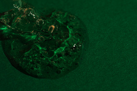 Transparent cosmetic serum drop with bubbles on green backgroundの写真素材