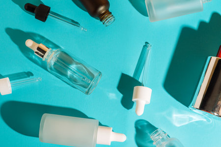 Glass cosmetic dropper bottles and pipettes on blue background. Skincare and beauty packaging concept.の写真素材