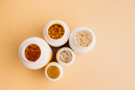 Mixed supplement containers top view on warm neutral background with copy space