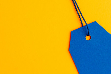 Close up blue price tag on yellow background with copy spaceの写真素材