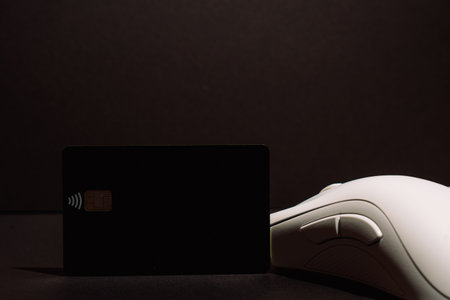 Contactless chip card standing by white gaming mouse on black backgroundの写真素材