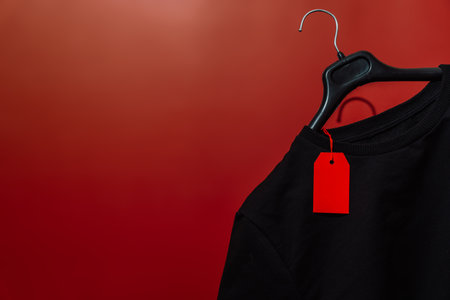 Red sale tag on black T-shirt and hanger copy spaceの写真素材