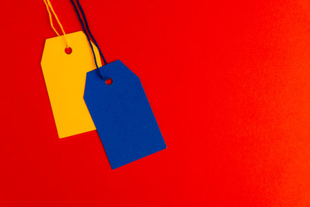 Blue yellow price tags on red background with copy spaceの写真素材