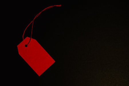 Red paper tag on black background, diagonalの写真素材