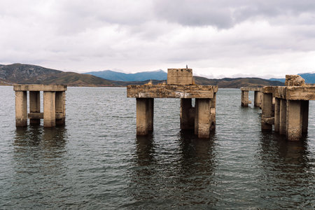 Abandoned concrete pillars standing in reservoir panoramaの写真素材