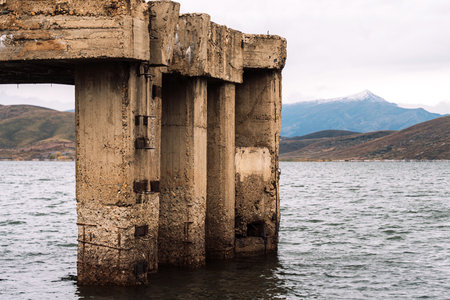 Aged concrete pier with distant snowy mountainの写真素材