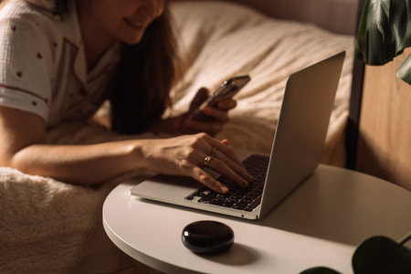 Woman using laptop and phone with AI home assistantの写真素材