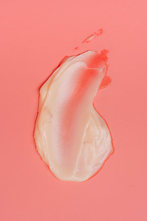 Smear of moisturizing cream on coral backgroundの写真素材