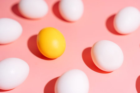 Minimal Easter egg pattern with one yellow egg among white eggs on pinkの写真素材