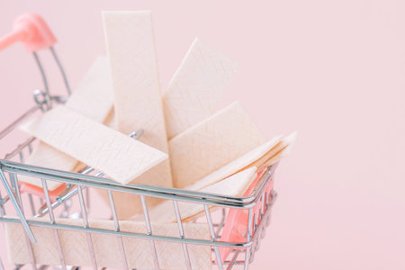 Close-up of miniature shopping cart filled with chewing gum sticks on pink backgroundの写真素材